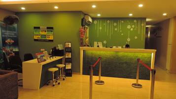 A reception area with a green wall, a reception desk, a phone, and a poster.