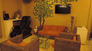A living room with a sofa, two armchairs, a coffee table, a TV, and a wall-mounted air conditioner. - Golden Leaf Boutique Hotel (Johor Bahru)