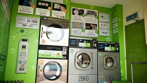 A laundromat with multiple washing machines, a dryer, and coin-operated machines. - Golden Leaf Boutique Hotel (Johor Bahru)
