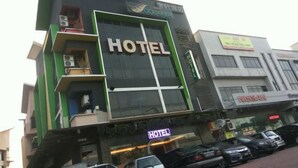 Een hotel met een groot 'HOTEL' bord, een Nissan autodealer en een parkeerplaats met meerdere auto's.