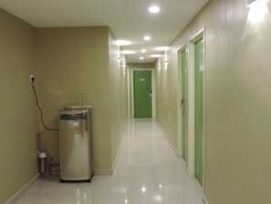 Un couloir avec un distributeur d’eau, une porte verte au fond et un sol propre.