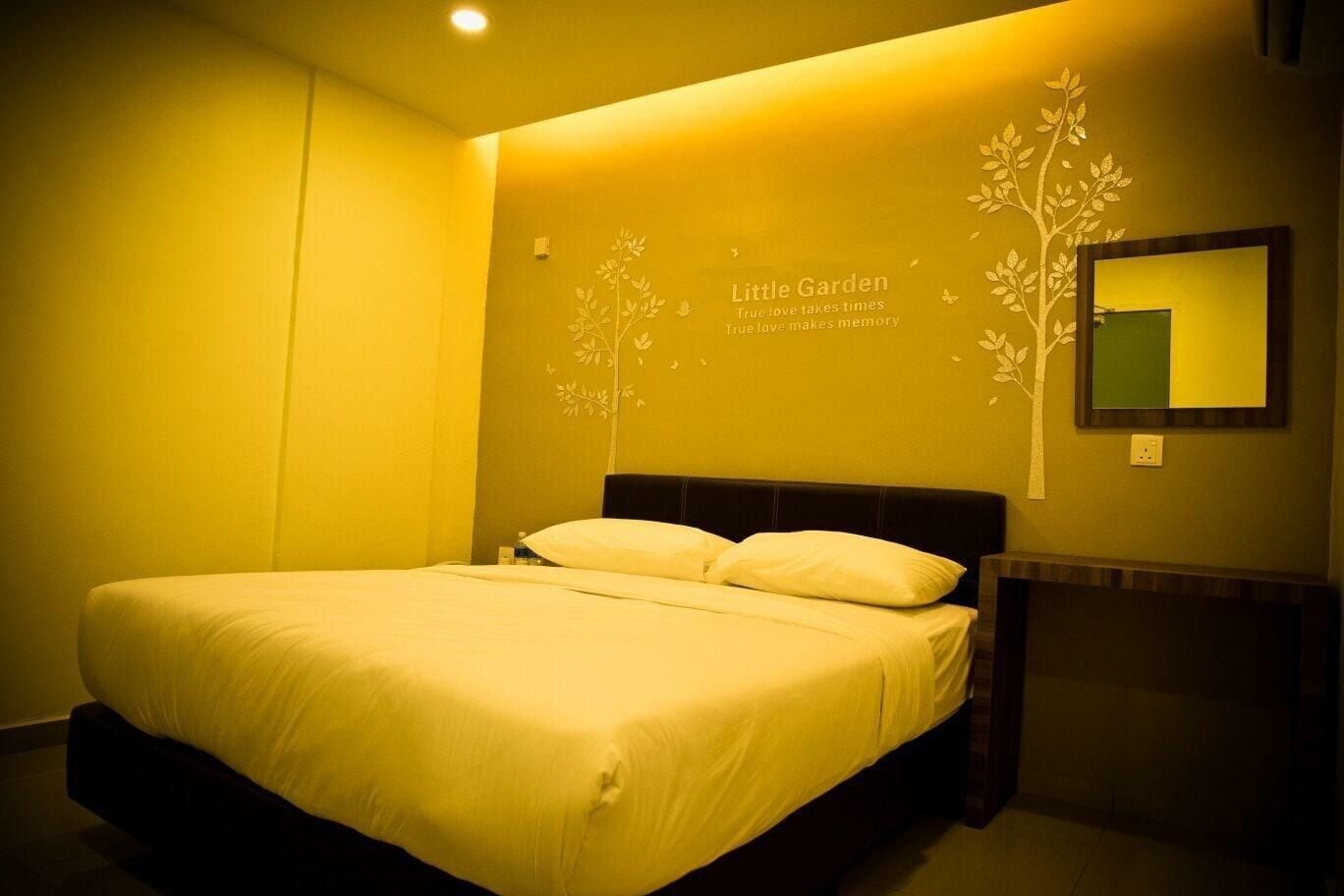 A hotel room with a bed, a wall-mounted mirror, and a decorative tree decal.