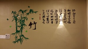A wall with calligraphy and a bamboo decoration. - Golden Leaf Boutique Hotel (Johor Bahru)