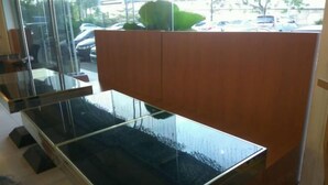 Een moderne kantoorruimte met een tafel met glazen blad, houten lambrisering en uitzicht op geparkeerde auto's.