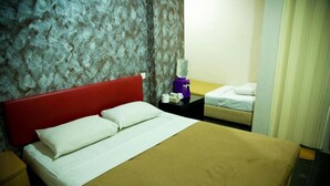 A hotel room with a large bed, a red headboard, a nightstand with a lamp, and a small table with a bottle. - Golden Leaf Boutique Hotel (Johor Bahru)