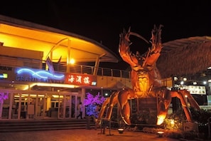 A large outdoor sculpture of a crab in front of a building with a thatched roof and illuminated signage. - Golden Leaf Boutique Hotel (Johor Bahru)