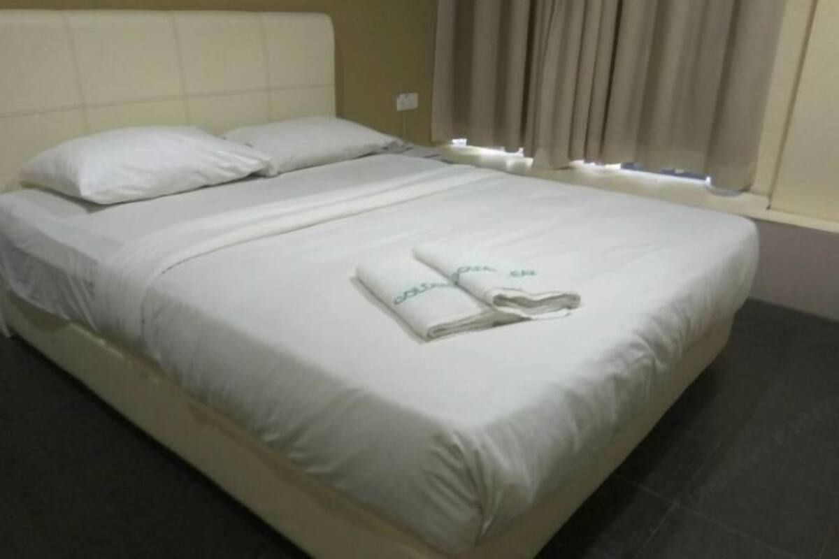 A neatly made bed with white linens and a folded towel on the footboard.