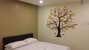 Une chambre avec un lit, un mur orné d’une fresque représentant un arbre et un interrupteur.