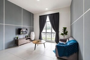 A modern living room with a sofa, a small round table, a TV, and a window with curtains. - DreamScape Apartment @ Golden Hill (Brinchang)