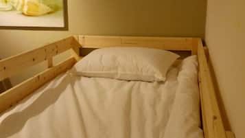 A single wooden bed with white bedding in a room with plain walls.