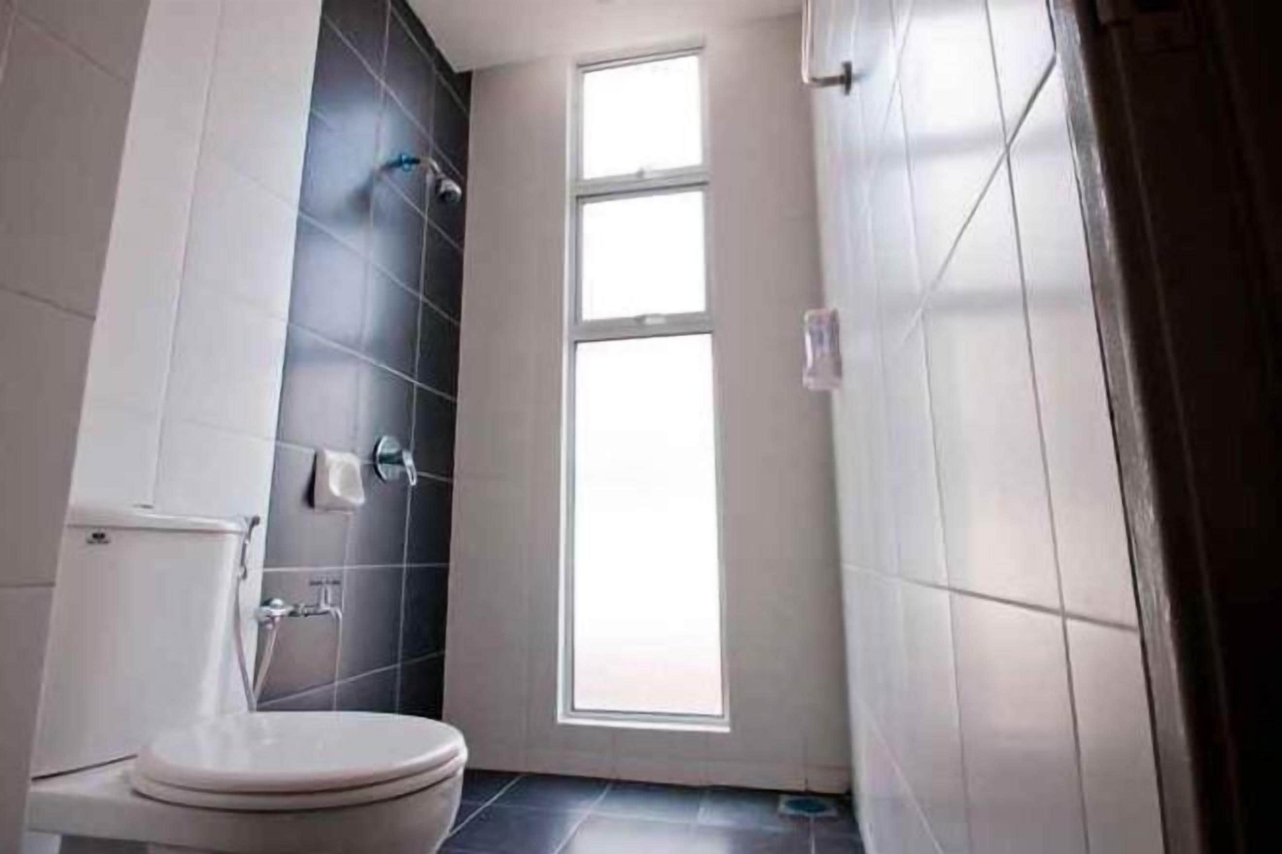 A bathroom with a toilet, a shower, and a window.