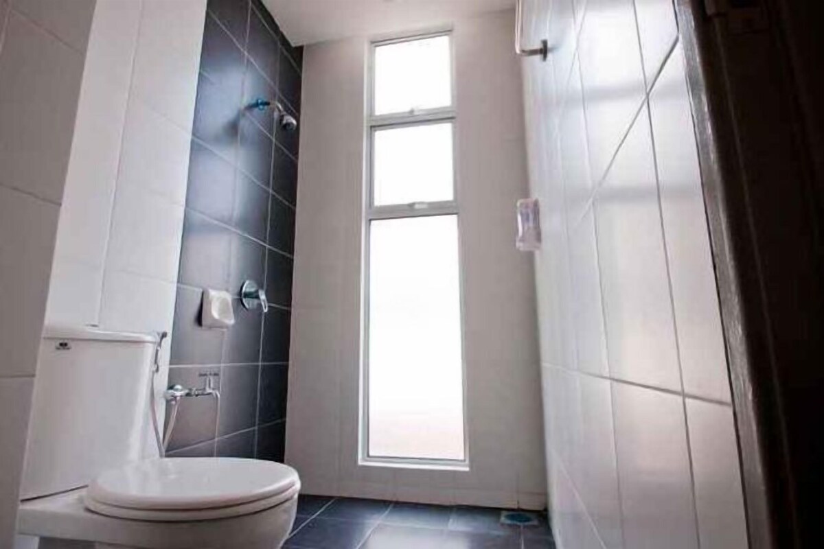 A bathroom with a toilet, a shower, and a window.