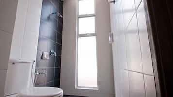 A bathroom with a toilet, a shower, and a window.