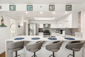 A modern kitchen with a central island, bar stools, and a backsplash with a geometric pattern.