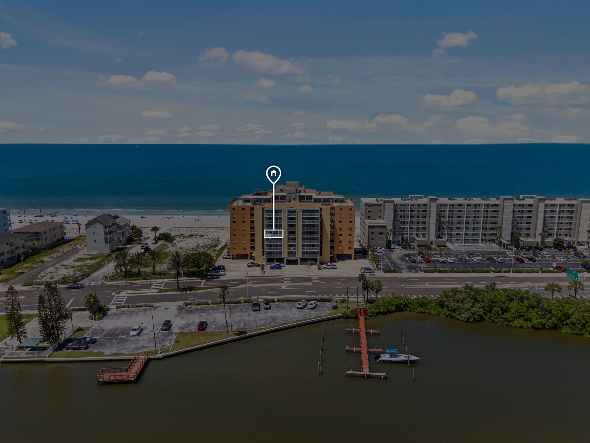 A multi-story hotel with a central courtyard, located near a beach and a marina.