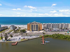 A coastal hotel with a parking lot, a marina, and a beach in the background. - Holiday Villas III - 410 Stunning Condo Intracoastal View Balcony , heated pool! (Indian Rocks Beach)