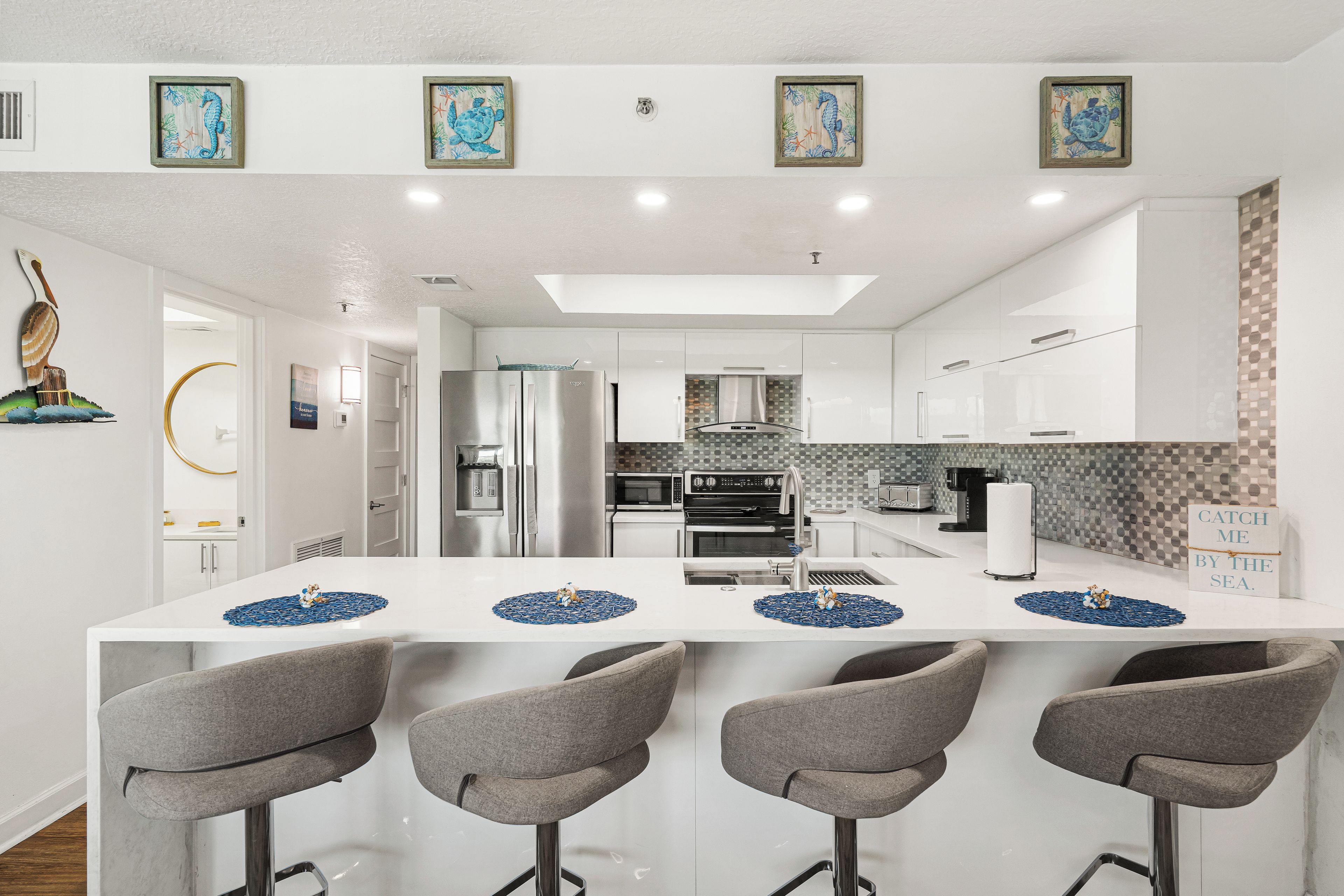 A modern kitchen with a central island, bar stools, and a backsplash with a geometric pattern.