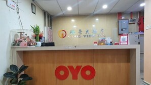 Un comptoir d’accueil avec un panneau en bois et un grand logo « OYO » rouge.