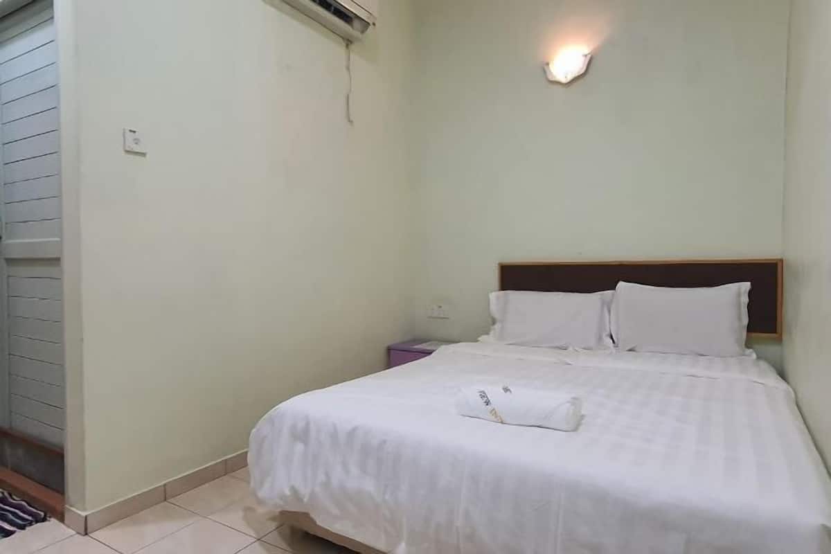 A single bed with white bedding, a wooden headboard, and a small bedside table with a lamp.