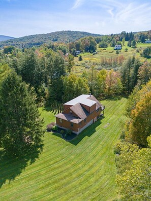 A large, single-story house with a sloped roof, surrounded by a well-maintained lawn and dense forest. - Modern Log Cabin Getaway | Summer Adventures & Game Room Fun (Margaretville)