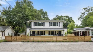 A two-story house with a front porch, a wooden fence, and a driveway. - The Duo at the Quad in Park Circle (North Charleston)