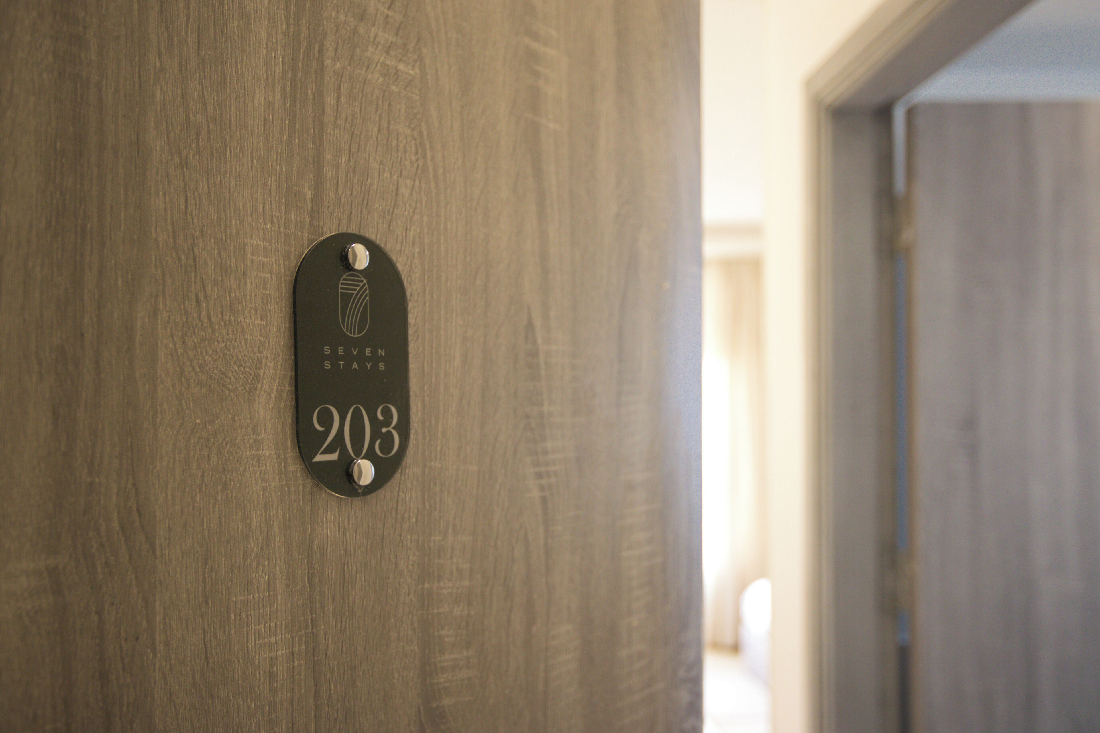 A wooden door with a metal plaque indicating room number 203.