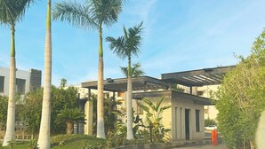 A modern building with a covered walkway, surrounded by palm trees and greenery. - Seven Stays Zayed (Sheikh Zayed City)