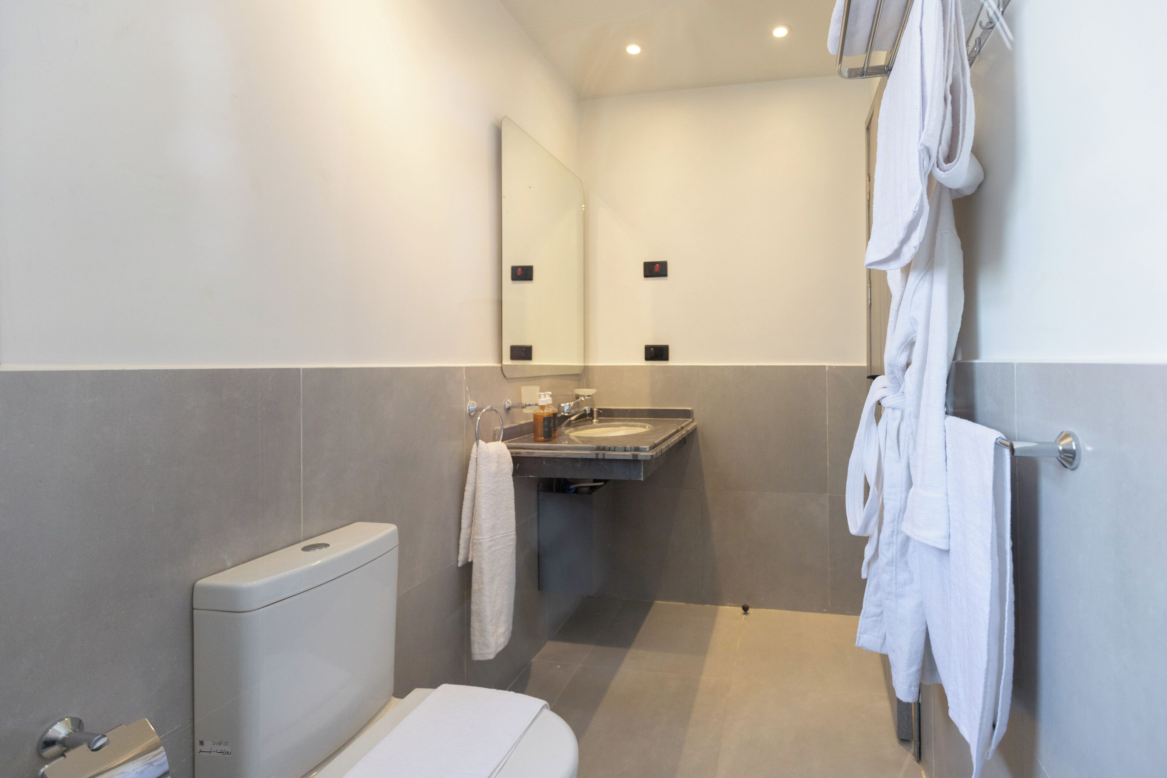 Un baño moderno con inodoro, lavamanos y toallero.