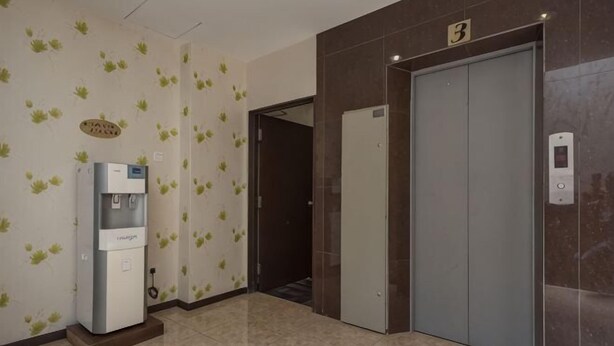 Um corredor com um bebedouro, uma porta com o número 3 e um elevador.