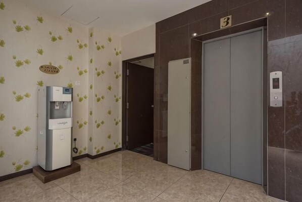 A hallway with a water dispenser, a door marked with the number 3, and an elevator.