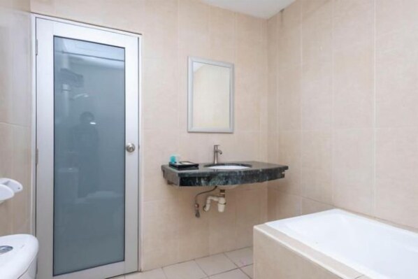 Et badeværelse med toilet, vask og badekar.