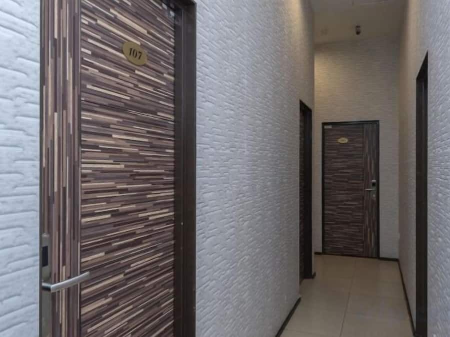 A narrow hallway with two doors, one with a number plate and the other with a keypad.