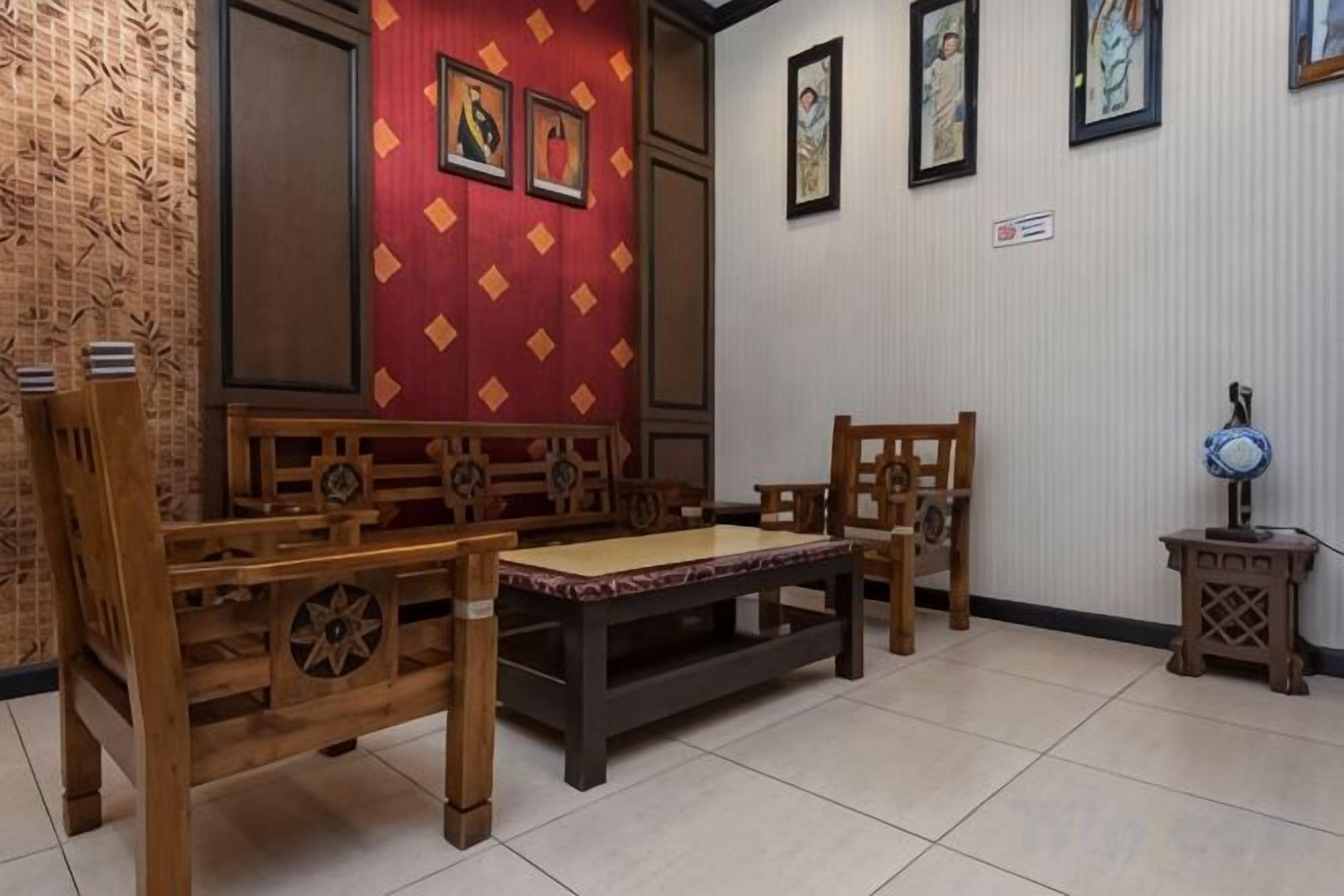 Una habitación con un sofá de madera tradicional, una mesita y una pared decorada con cuadros.