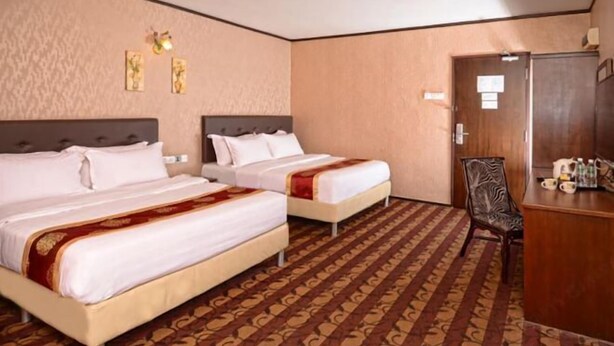 Une chambre d’hôtel avec deux lits, un bureau et une chaise.