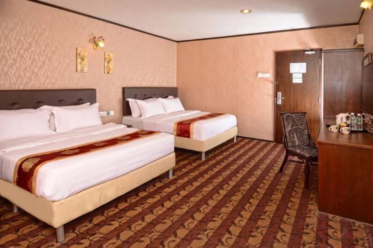 Een hotelkamer met twee bedden, een bureau en een stoel.