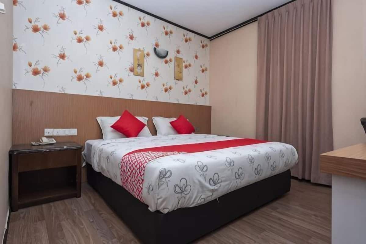 Een hotelkamer met een bed, nachtkastje en een bureau.