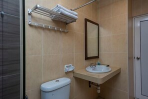A bathroom with a toilet, sink, mirror, towel rack, and a shower area. - Suan Bee Hotel@Sutera (Sekudai)