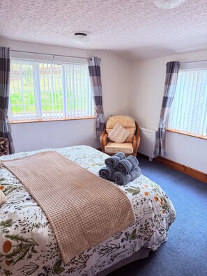 A bedroom with a bed, a chair, a window with curtains, and a view of greenery outside. - Cosy Corner Suite of Rooms at Trelogan Hall, Grade II Listed House. (Trelogan)
