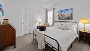 A neatly arranged bedroom with a bed, bedside tables, a dresser, and a painting on the wall. - 3BR Walkable Downtown Retreat ~ King Bed + Porch (Salisbury)