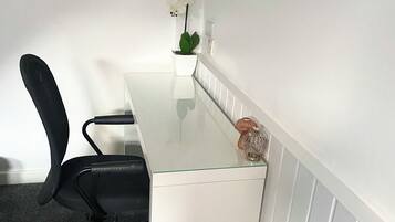 Una sala de conferencias con una mesa blanca, una silla de oficina negra y una orquídea en maceta.