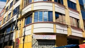 A multi-story building with a curved facade, featuring a storefront at the ground level. - Hostal Iskanwaya (La Paz)
