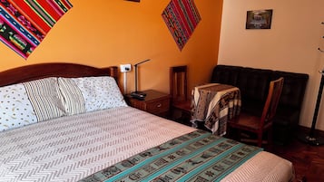 A hotel room with a large bed, a desk, a chair, and a small table.