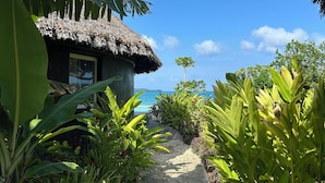 A thatched-roof building with a pathway leading to a beach. - Black Pearl Resort  (Saraotou)