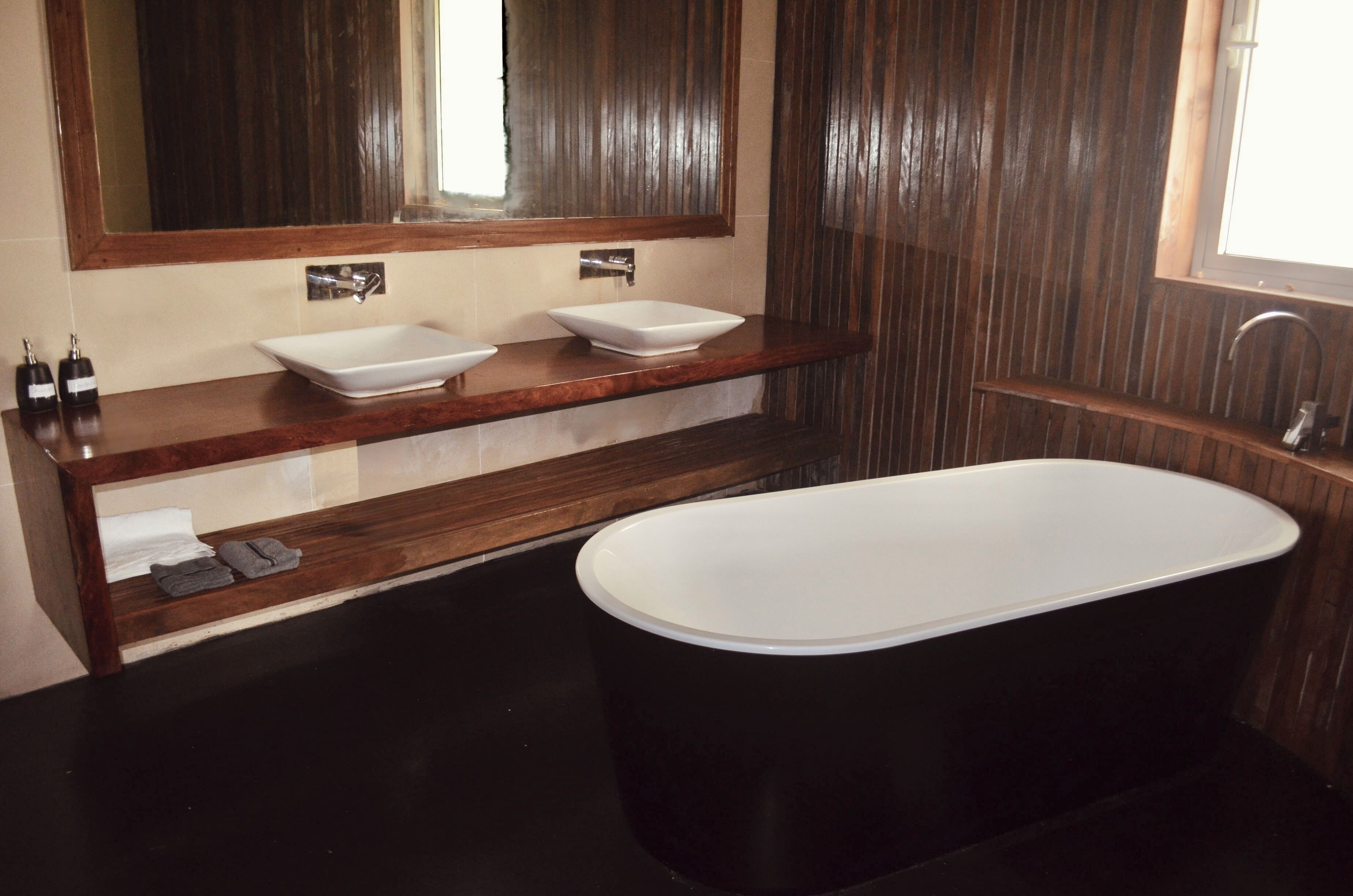 A modern bathroom with a freestanding bathtub, two sinks, and a large mirror.