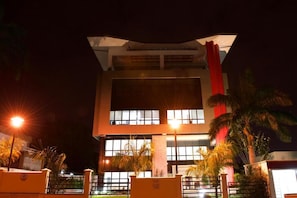 A modern building with multiple floors, large windows, and a prominent red vertical element.