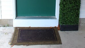 Una puerta principal verde, un buzón y una escultura decorativa con forma de hongo.