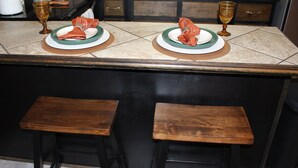 Una isla de cocina con dos taburetes, un lavamanos y una encimera con un escurreplatos.