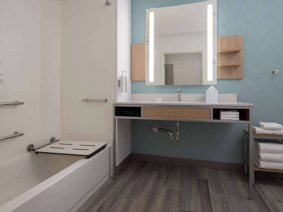 Un baño moderno con una bañera, un lavamanos con espejo y un perchero para toallas.