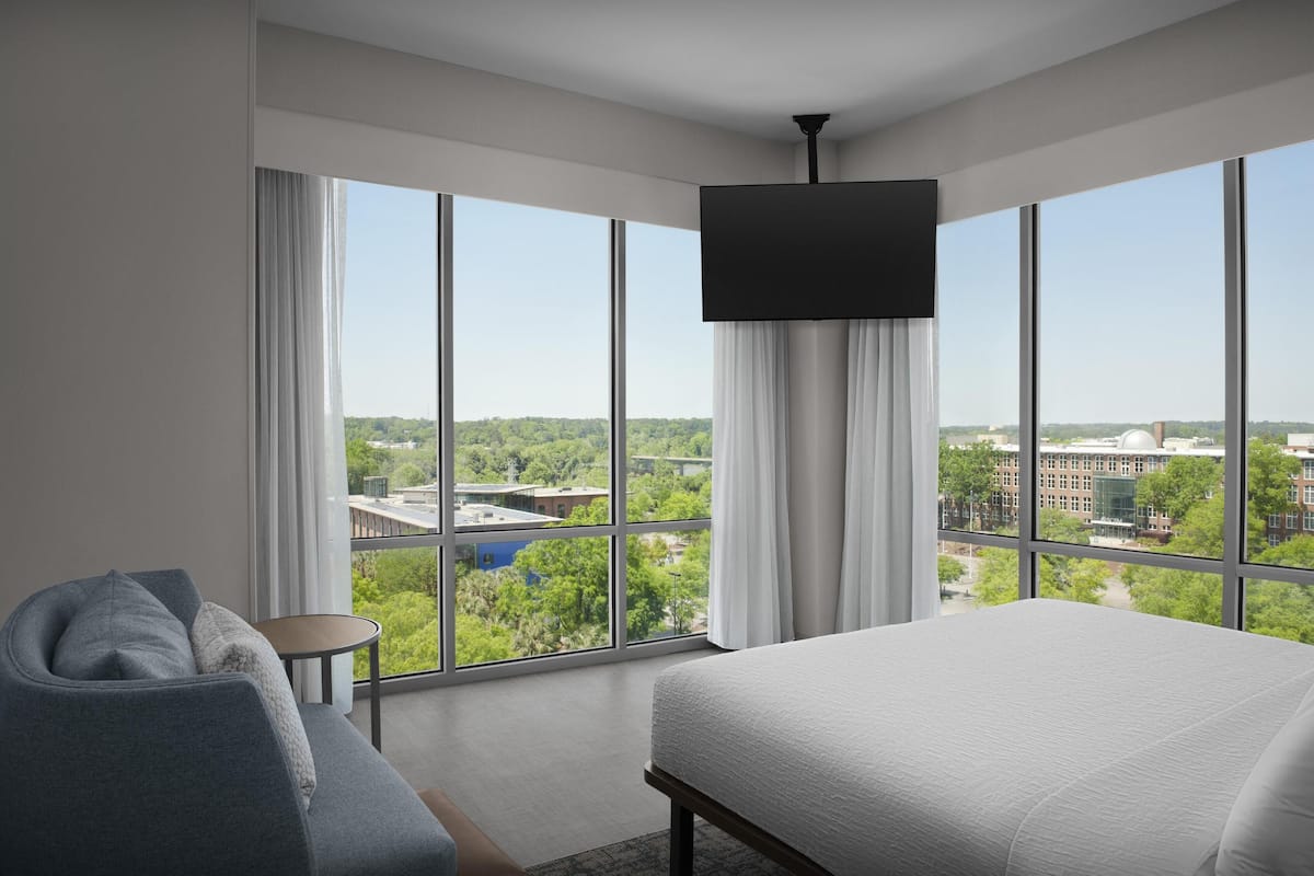 Une chambre d’hôtel moderne dotée d’un grand lit, d’un coin salon et d’une télévision.