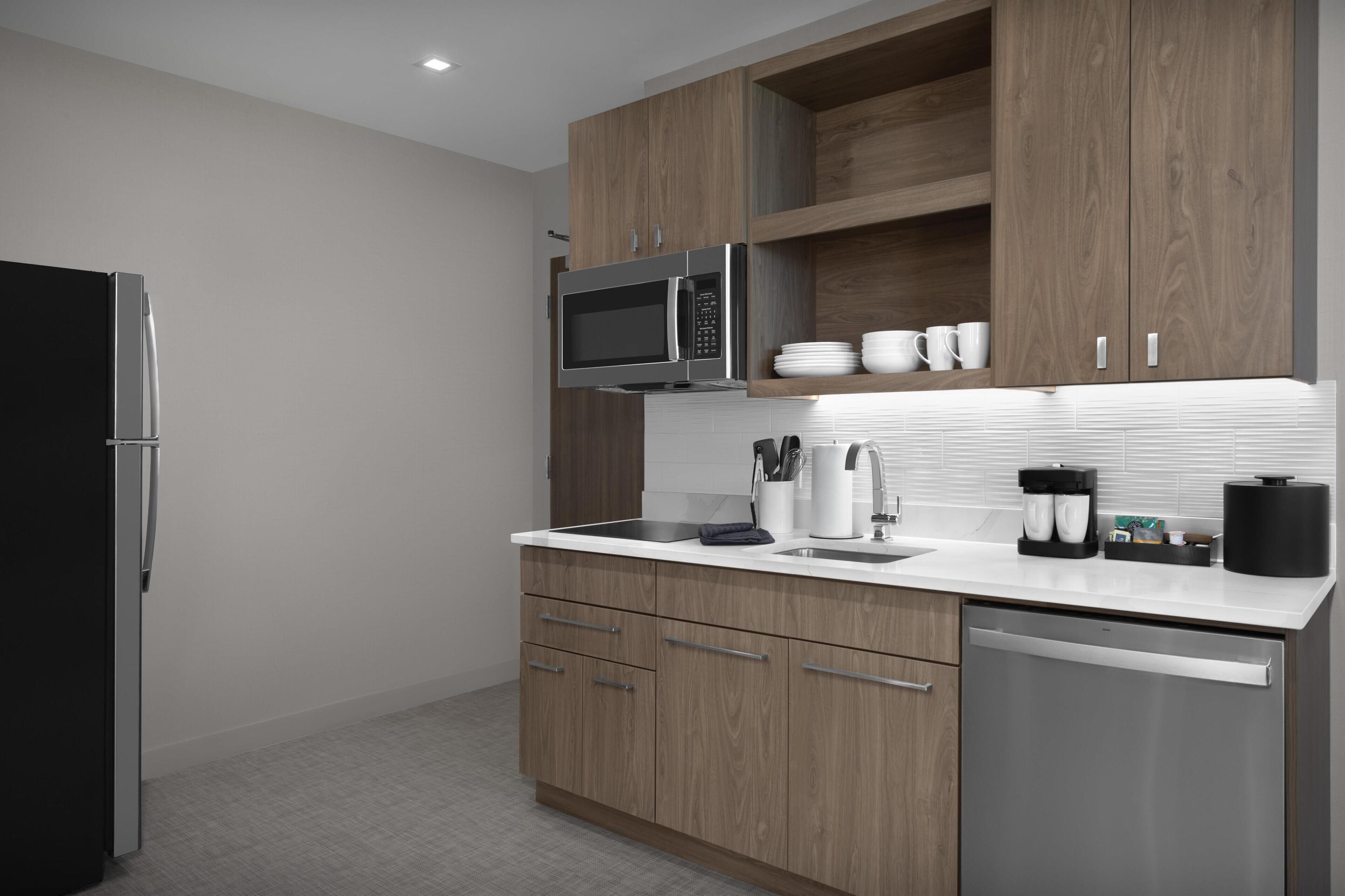 Una cocina moderna con armarios de madera, un refrigerador de acero inoxidable, un microondas y un lavavajillas.